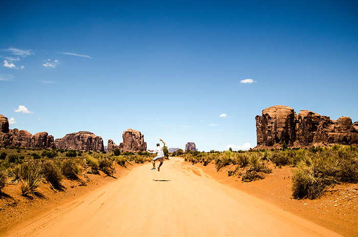 a happy man clicks heels mid jump on a dirt track in the desert