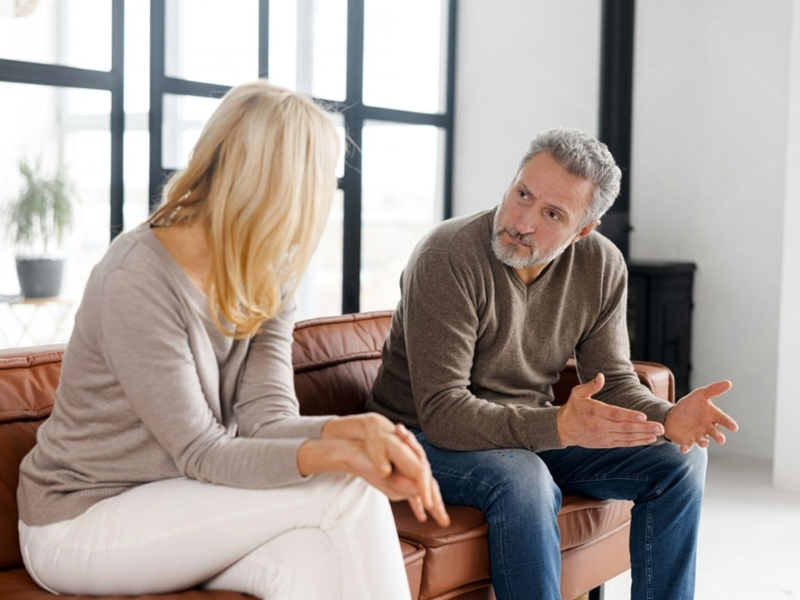 Mature couple having a calm and serious conversation on a sofa representing open communication about male sexual health and low sex drive